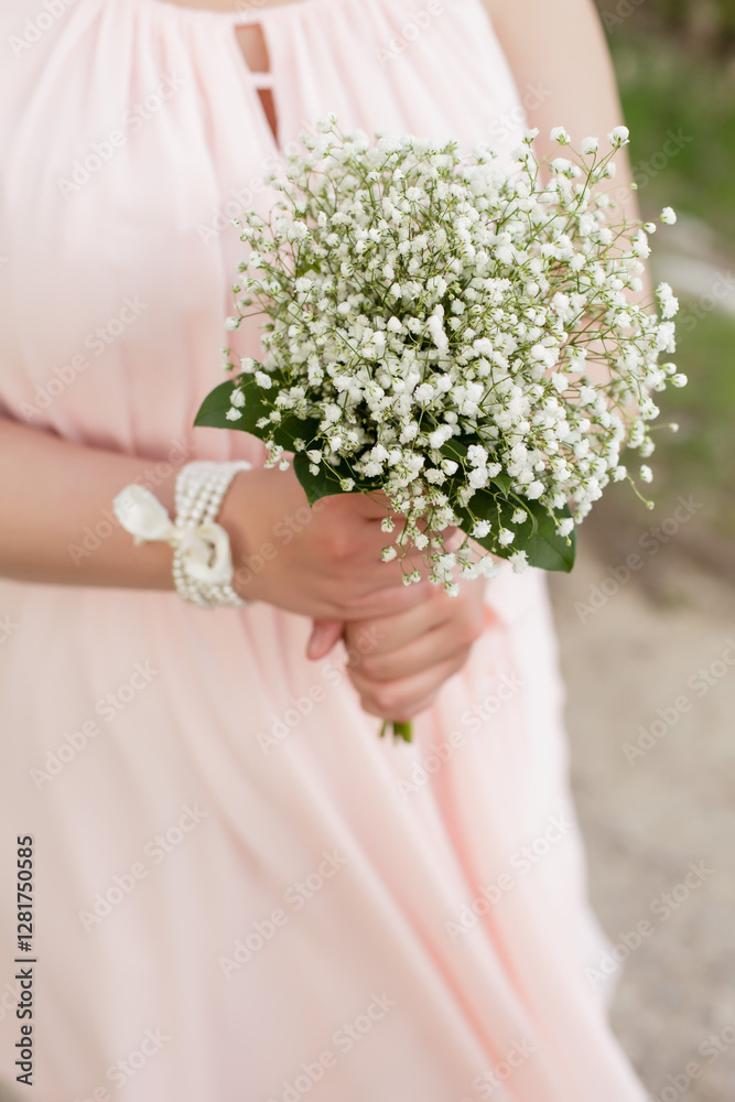 Woman in a soft pink dress holding a bouquet of baby's breath flowers Woman in a soft pink dress holding a bouquet of baby's breath flowers