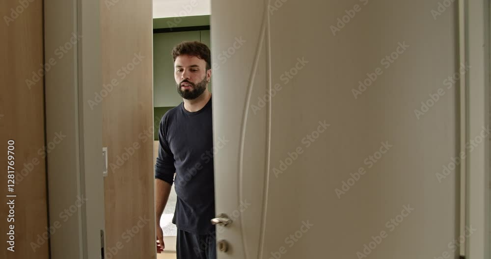 A young Caucasian man wakes up in his modern apartment, stretches, and yawns as he starts his day. A young Caucasian man wakes up in his modern apartment, stretches, and yawns as he starts his day.
