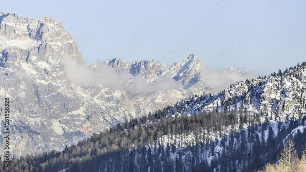 Moving clouds around a majestic snow-capped rocky peak in the Dolomites in winter - time lapse