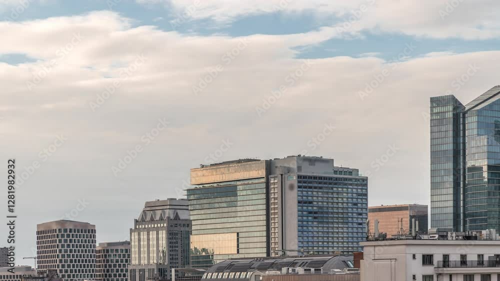 Aerial timelapse of modern skyscrapers and towers in Brussels with glass facades reflecting cloudy sky. Evening urban skyline featuring business area with rooftops before sunset. Belgium