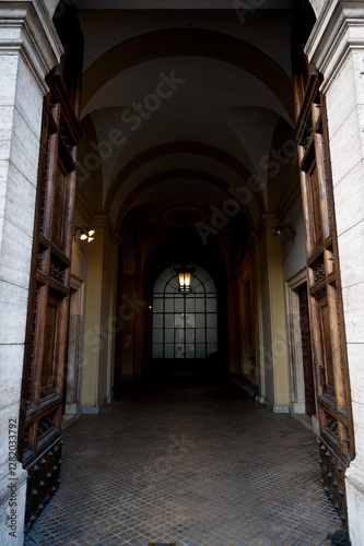 A grand arched hallway with open wooden doors and a glowing lantern