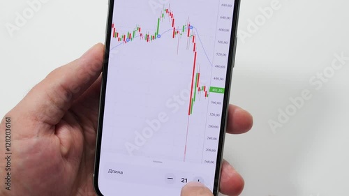 Smartphone screen displaying falling stock market graph, representing financial volatility and economic uncertainty during challenging investment landscape
