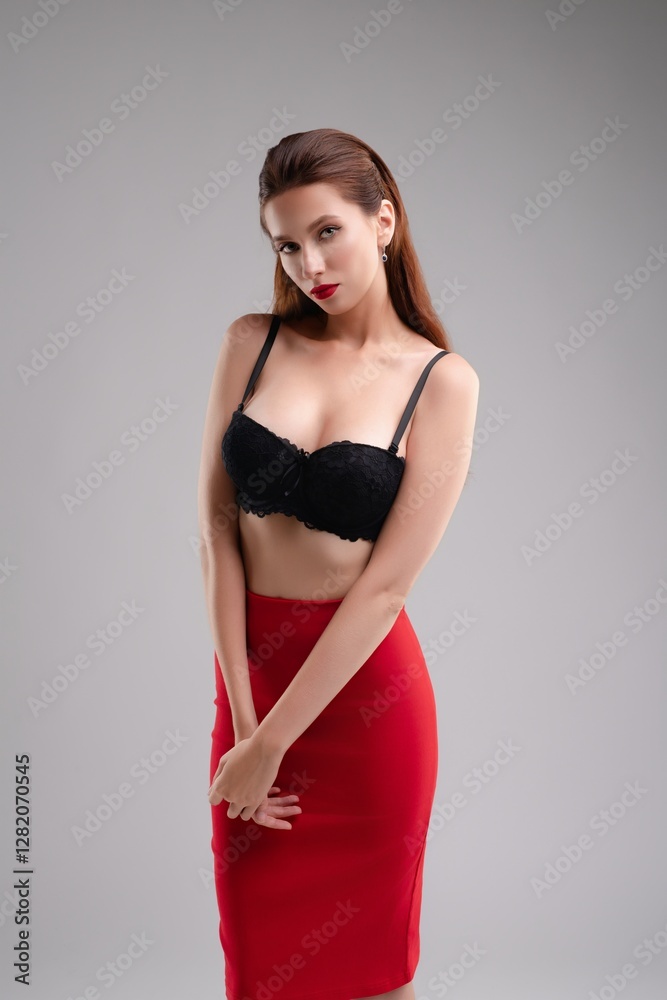 Fototapeta premium Elegant woman poses confidently in lingerie against studio backdrop