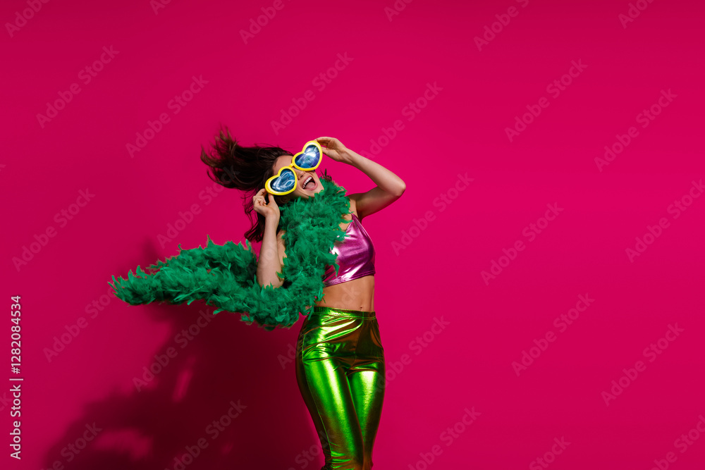 Fototapeta premium Trendy Young Woman in Colorful Outfit Posing Against Bright Pink Background While Expressing Joyful Emotions During a Celebration