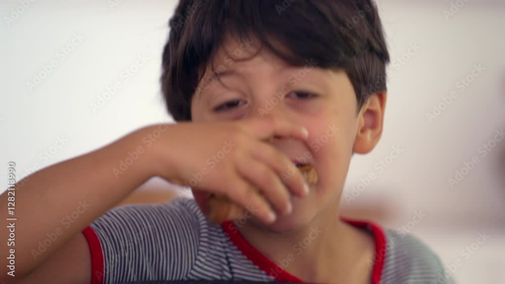 Young boy eating snack, enjoying bite of cookie, playful expression, indoor moment, casual snacking, child indulging in food, happy childhood moment, relaxed atmosphere Young boy eating snack, enjoying bite of cookie, playful expression, indoor moment, casual snacking, child indulging in food, happy childhood moment, relaxed atmosphere