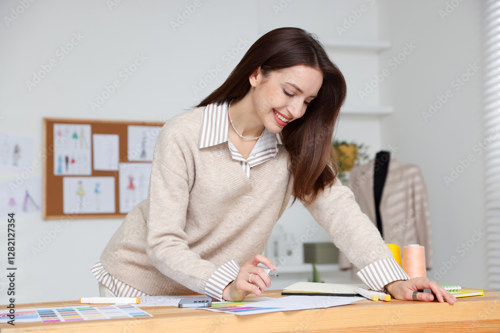 Fashion designer drawing sketch of stylish clothes at wooden table in workshop Fashion designer drawing sketch of stylish clothes at wooden table in workshop