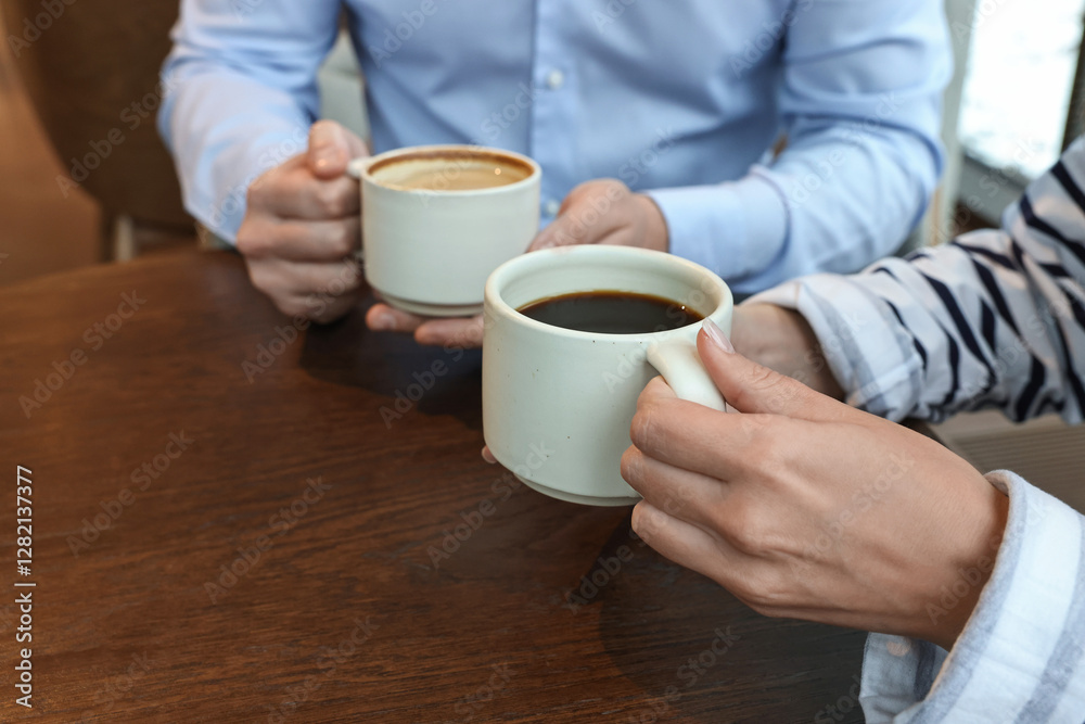 Colleagues having coffee break at wooden table in cafe, closeup Colleagues having coffee break at wooden table in cafe, closeup