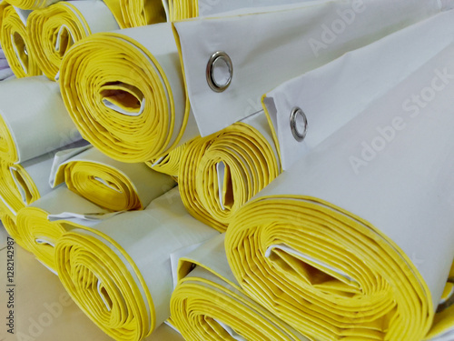 a bunch of rolled up banners on the printing industry floor. stacks of packed products. white tarpaulin printed with yellow