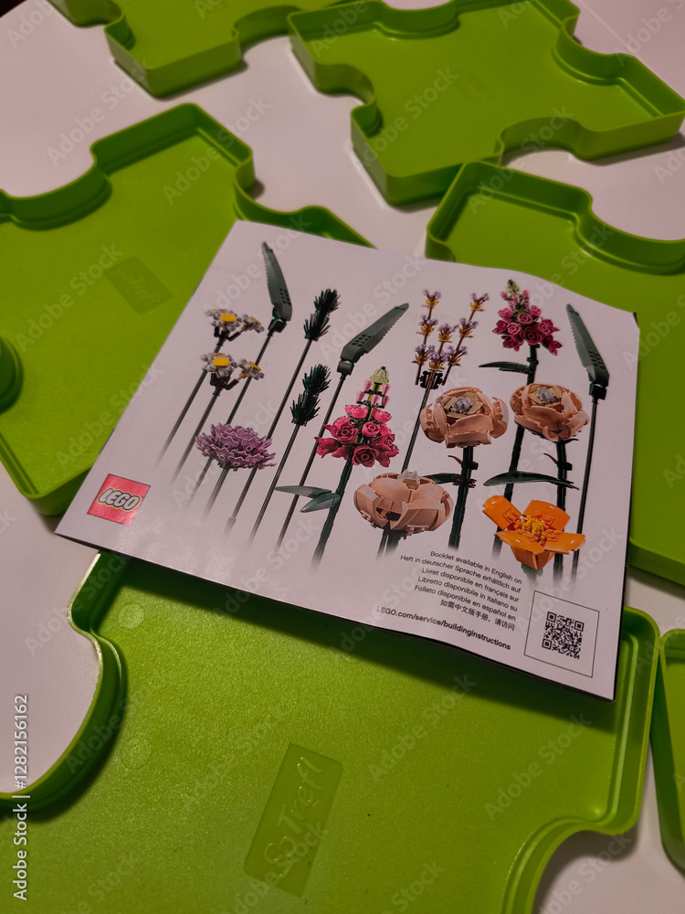 Naklejka premium Prague, Czech republic - February 20, 2025: Lego flower bouquet instruction booklet lying on green sorting trays
