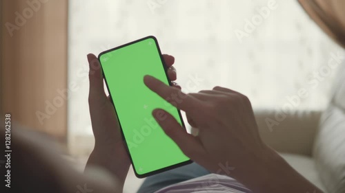 Woman Lying on Couch Using Smartphone With Chroma Key Green Screen Scrolling Through Social Media. Girl Mobile Phone Using Green Screen Female Using Smartphone Browsing Internet Watching Video Content