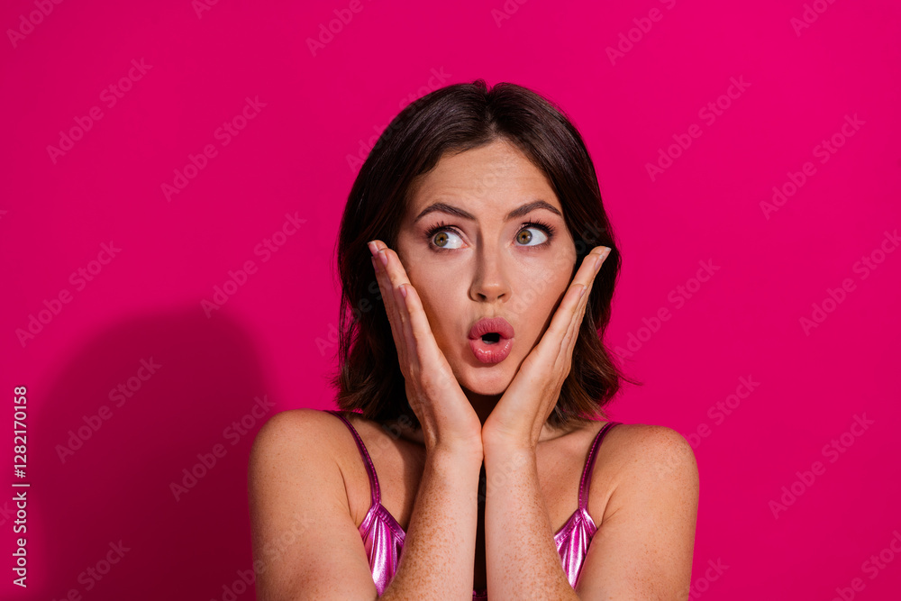 Charming woman in shiny pink top posing against a vivid magenta background showcasing surprise gesture with hands Charming woman in shiny pink top posing against a vivid magenta background showcasing surprise gesture with hands