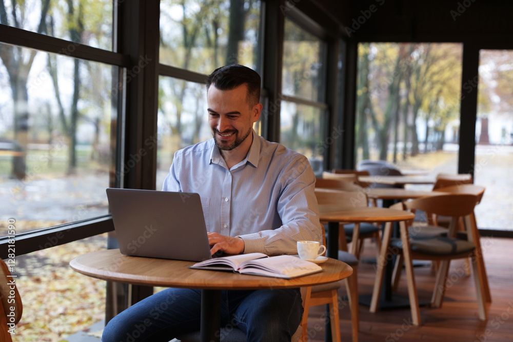 Man working on laptop at table in cafe Man working on laptop at table in cafe