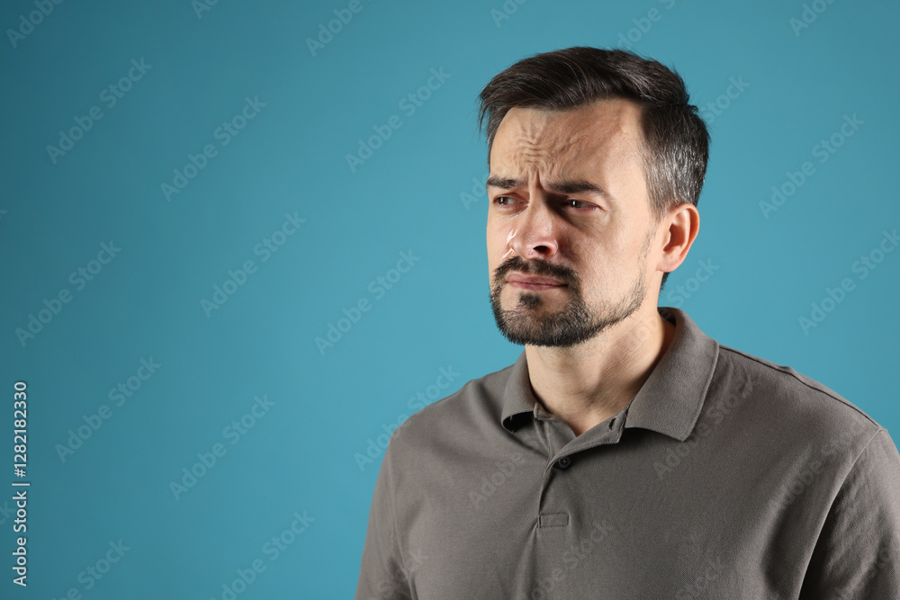 Sad man crying on light blue background, space for text Sad man crying on light blue background, space for text