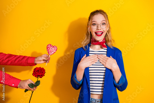 Excited young woman wearing stylish outfit on a vibrant yellow background, surprised with gifts photo