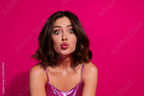 Smiling Young Woman Posing with Puckered Lips on a Bright Pink Background Wearing a Shiny Blouse