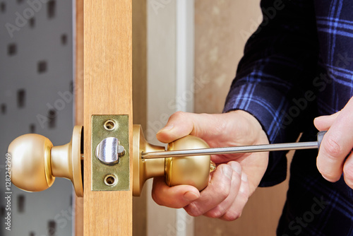 Door installer secures handle and latch to interior door using hand screwdriver.