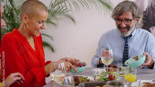 Smiling Caucasian family sitting at table passing food to each other at indoor festive event. Happy people of different generations enjoying lunch together at domestic life