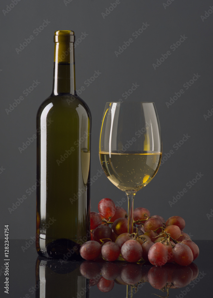 Obraz premium Elegant presentation of gray wine bottle and glass with grapes on a reflecting surface