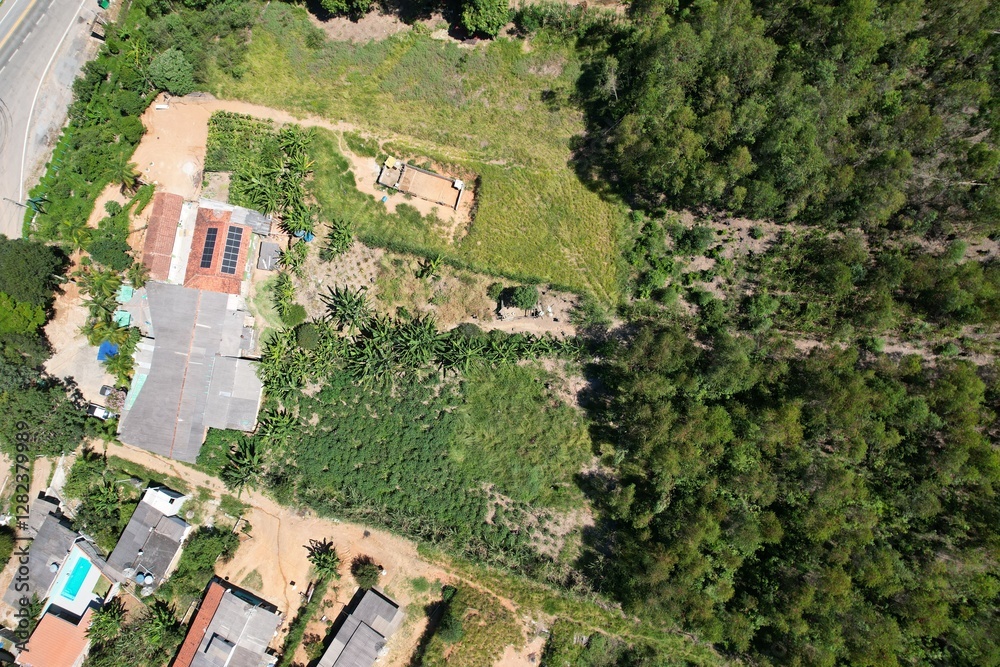 Fototapeta premium Contraste das casas em uma área de expansão urbana sobre a floresta, em uma área localizada no interior do estado de São Paulo, Brasil, em uma imagem aérea obtida com drone.