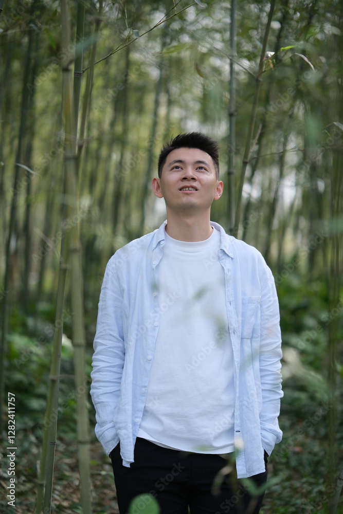 Asian young man at bamboo grove, looking up Asian young man at bamboo grove, looking up