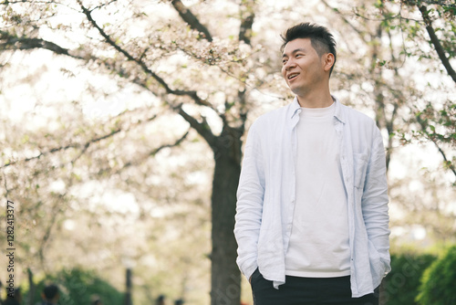 happy smiling Asian young man and sakura blossom tree