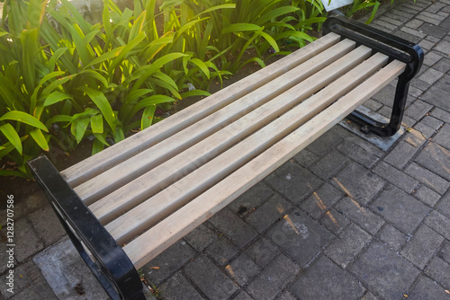 A long wooden chair in the garden is exposed to the morning sun