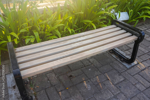 A long wooden chair in the garden is exposed to the morning sun