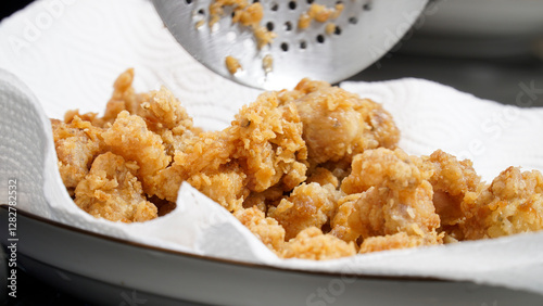 Billede på lærred Crispy fried chicken pieces resting on a paper towel, absorbing excess oil, showcasing their golden-brown texture