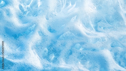 Abstract close-up of light blue soapy water texture, with background of rippled foam