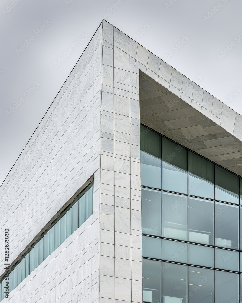 Modern architectural design featuring geometric lines and glass facade during cloudy day Modern architectural design featuring geometric lines and glass facade during cloudy day