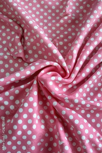 Pink fabric with white polka dots texture draped and folded on a surface details of textile pattern surface design photo