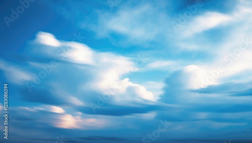 Blue sky with soft white clouds in a blurred motion effect creating a peaceful atmosphere and a sense of tranquility.
