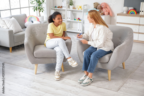 African-American girl talking to psychologist in armchairs at office