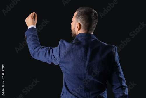 Businessman writing on dark...
