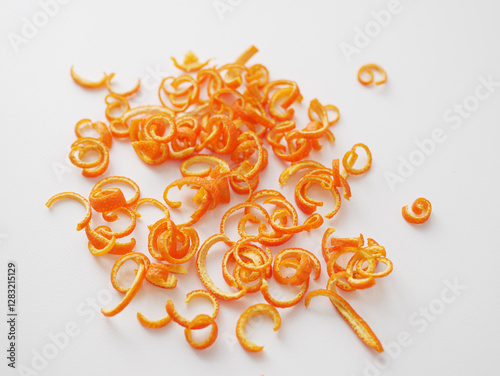 Orange peel forming curls on white background for baking and cocktails