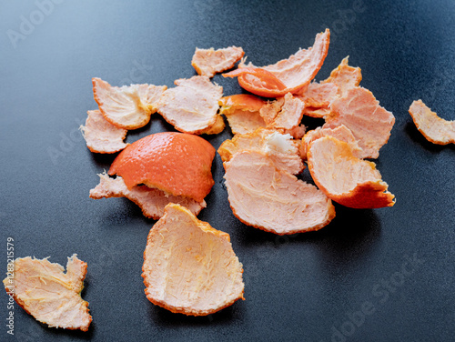 Mandarin orange peel scattered on dark background