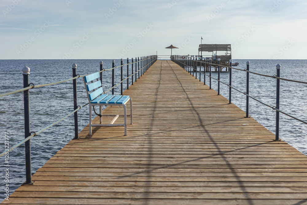 Wooden pier with blue bench stretching into the red sea in marsa alam, egypt Wooden pier with blue bench stretching into the red sea in marsa alam, egypt