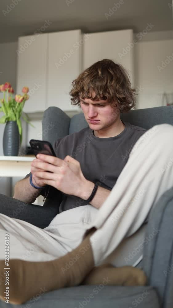 Vertical screen: The person looks frustrated and confused, intensely focusing on their phone, possibly trying to understand something troubling or perplexing on the screen. Vertical screen: The person looks frustrated and confused, intensely focusing on their phone, possibly trying to understand something troubling or perplexing on the screen.