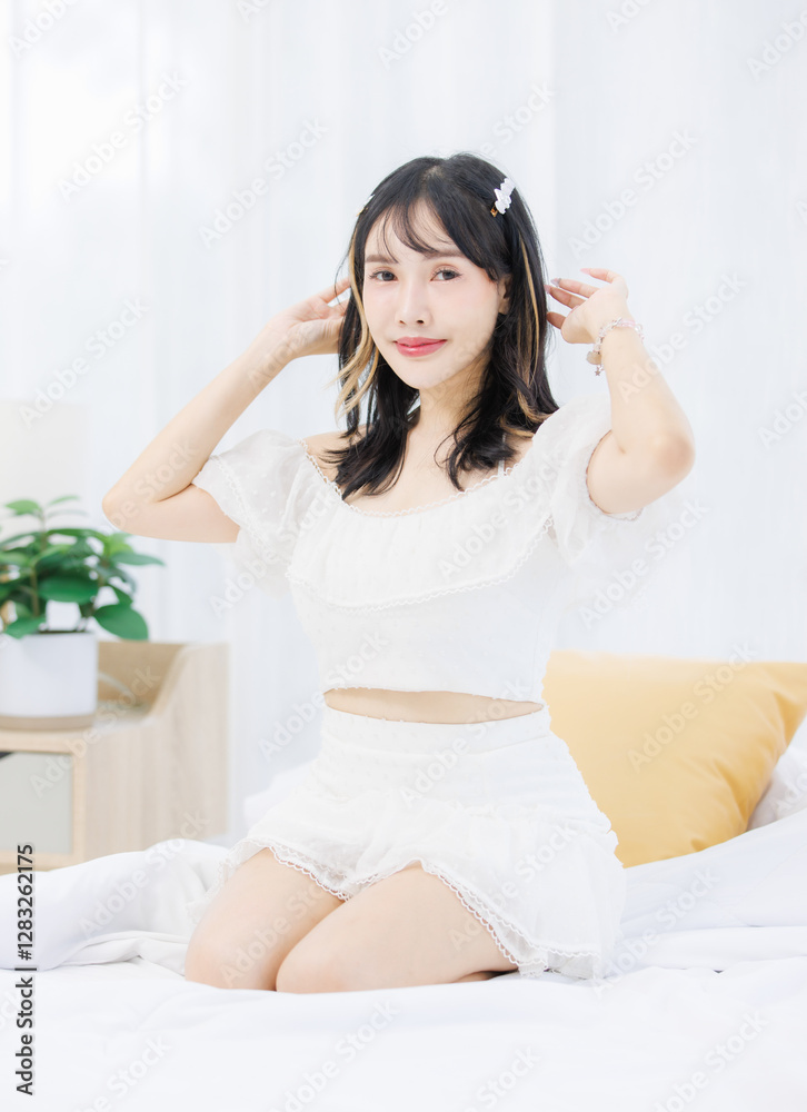 Asian happy young beautiful cheerful female sitting on cozy white bed smiling looking around in bedroom at home, Good morning calm comfortable healthcare relaxing resting well being peaceful concept. Asian happy young beautiful cheerful female sitting on cozy white bed smiling looking around in bedroom at home, Good morning calm comfortable healthcare relaxing resting well being peaceful concept.