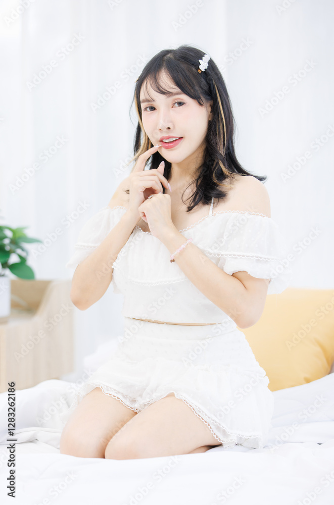 Asian happy young beautiful cheerful female sitting on cozy white bed smiling looking around in bedroom at home, Good morning calm comfortable healthcare relaxing resting well being peaceful concept. Asian happy young beautiful cheerful female sitting on cozy white bed smiling looking around in bedroom at home, Good morning calm comfortable healthcare relaxing resting well being peaceful concept.