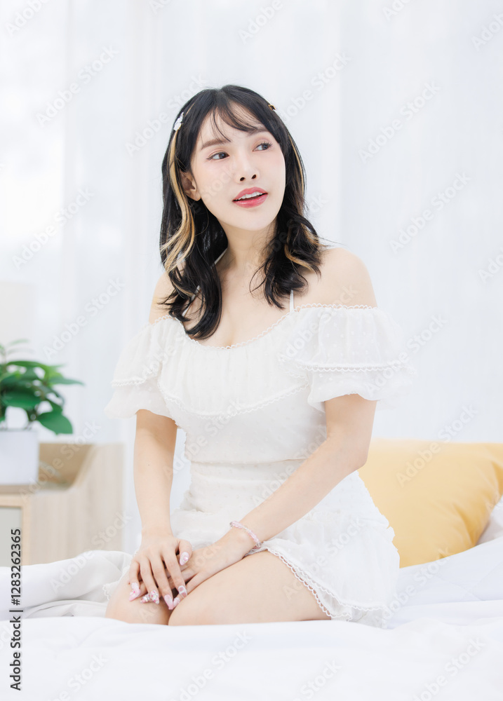 Asian happy young beautiful cheerful female sitting on cozy white bed smiling looking around in bedroom at home, Good morning calm comfortable healthcare relaxing resting well being peaceful concept. Asian happy young beautiful cheerful female sitting on cozy white bed smiling looking around in bedroom at home, Good morning calm comfortable healthcare relaxing resting well being peaceful concept.