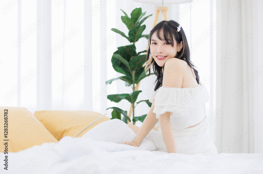 Asian happy young beautiful cheerful female sitting on cozy white bed smiling look at camera in bedroom at home, Good morning calm comfortable healthcare relaxing resting well being peaceful concept. Asian happy young beautiful cheerful female sitting on cozy white bed smiling look at camera in bedroom at home, Good morning calm comfortable healthcare relaxing resting well being peaceful concept.