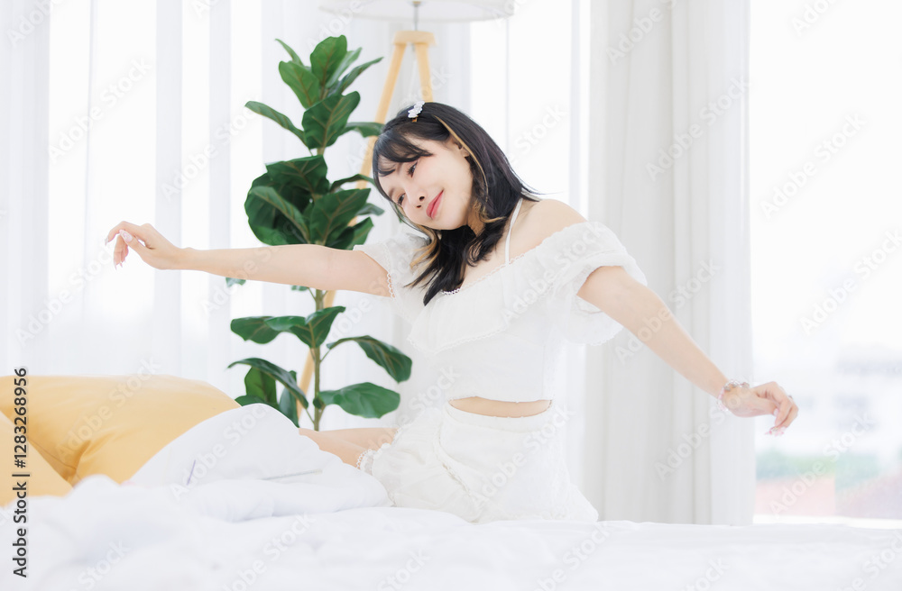 Asian happy young beautiful cheerful female sitting on cozy white bed smiling look at camera in bedroom at home, Good morning calm comfortable healthcare relaxing resting well being peaceful concept. Asian happy young beautiful cheerful female sitting on cozy white bed smiling look at camera in bedroom at home, Good morning calm comfortable healthcare relaxing resting well being peaceful concept.