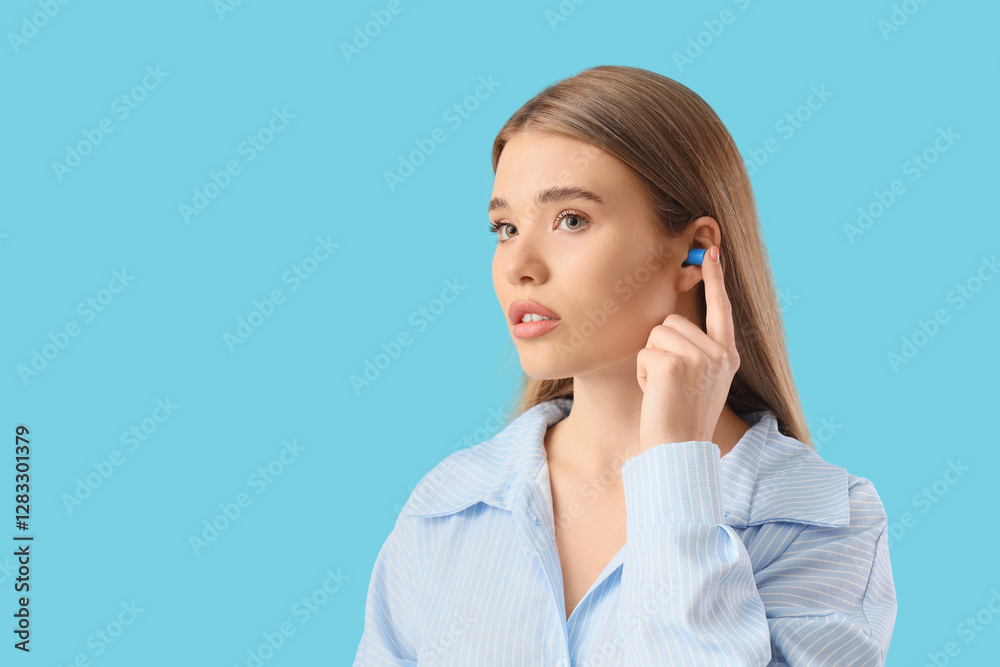 Young woman in pajamas with earplug on blue background, closeup Young woman in pajamas with earplug on blue background, closeup