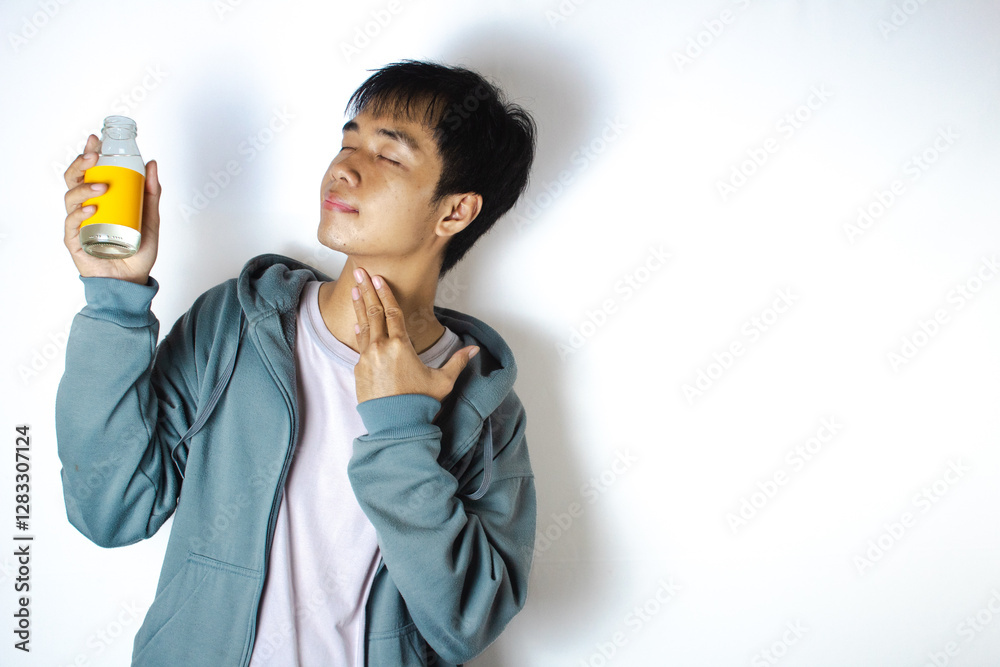 Asian teenager in white t-shirt and blue hoodie, posing quenching thirst with a drink in his hand