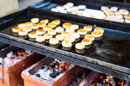 A seller grills bakpia on hot charcoal. Bakpia is one of Indonesian traditional food. Delicious Bakpia at Ngasem market (traditional market) in Yogyakarta, Indonesia. photo