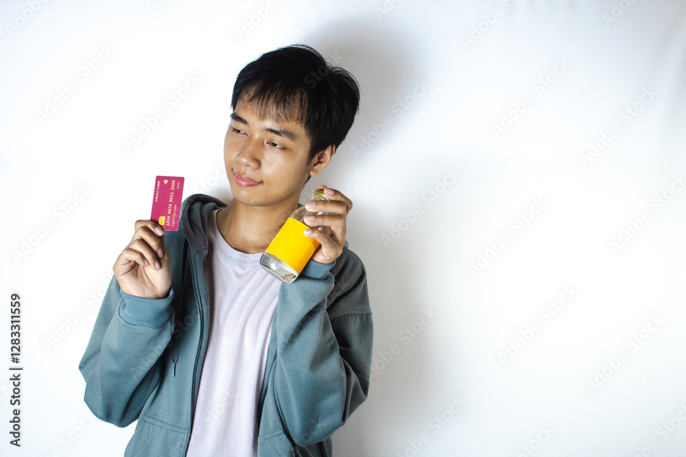 Asian teenager in white t-shirt and blue hoodie, posing with a sweet smile with his credit card and glass Asian teenager in white t-shirt and blue hoodie, posing with a sweet smile with his credit card and glass