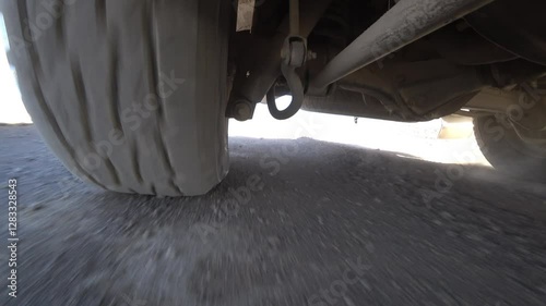 The camera is fixed on the bottom of the car, a view of the wheel and suspension while driving. Off-road, rocks and dust. The suspension works well off-road and bumps. Deserted area. Tire deformation