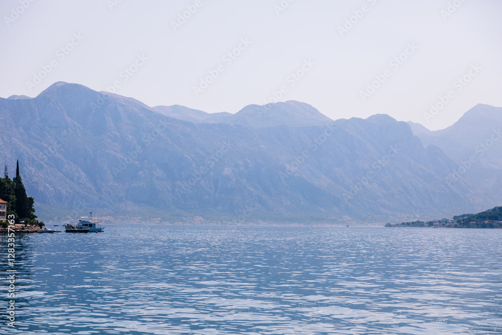 Serene mountain scenery with calm waters and distant boats Serene mountain scenery with calm waters and distant boats