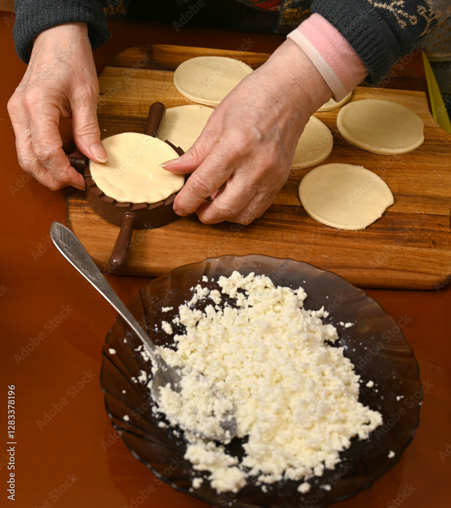 Woman skillfully fills dough circles with cheese in a warm kitchen